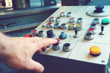 The worker uses the control panel of the CNC machine to process the material.