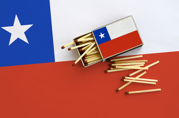 Chile flag  is shown on an open matchbox, from which several matches fall and lies on a large flag