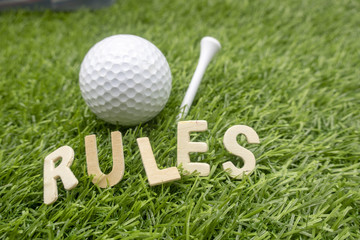 rules of golf with golf ball and wording rules are on green grass