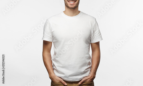 Fotografía Handsome man in white tshirt isolated on grey background, smiling, standing in h