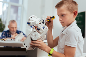 Wall Mural - future engineer. serious young boy holding a screwdriver while building a robot