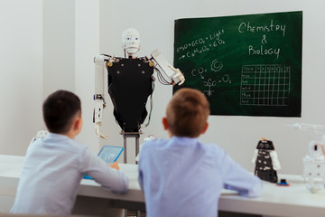 Wall Mural - progressive education. smart self driven robot standing near the blackboard while conducting a lesso