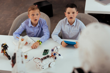 Wall Mural - new innovations. surprised teenager boys sitting at the school dest while looking at their new teach