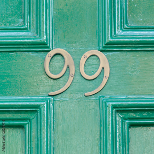Photographie Brass house number 99 sign on green painted door