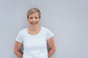 Smiling young woman leaning against wall