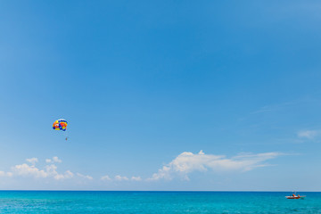 Wall Mural - People flying on a colorful parachute towed by a motor boat