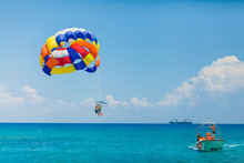 Couple Of Tourists Flying On A Colorful Parachute
