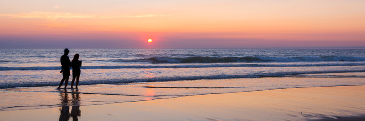 Wall Mural - silhouettes of a couple enjoying the sunset on the atlantic ocean, lacanau france