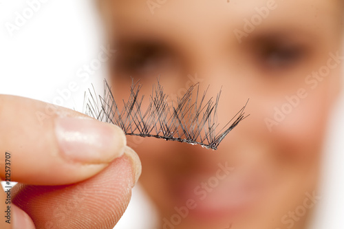 Fotografía young woman holding her false eyelashes on white background