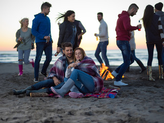  Couple enjoying with friends at sunset on the beach