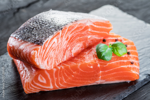 Fotomural Fresh salmon fillets on black cutting board with herbs and spices