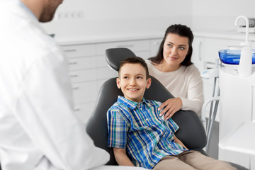 Poster - medicine, dentistry and healthcare concept - mother and son visiting dentist at dental clinic