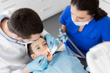 Canvas Print - medicine, dentistry and healthcare concept - dentist with mouth mirror and probe checking for kid patient teeth at dental clinic