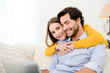 © W PRODUCTION - cheerful young couple on sofa at home websurfing and shopping online with laptop computer internet technology