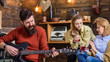 © be free - Man with long bushy beard singing passionately, music concept. Girls drinking tea or wine and enjoying lovely tunes. Bearded man playing guitar. Guitarist with hipster beard performing new song
