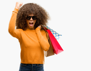 Canvas Print - African american woman holding shopping bags annoyed and frustrated shouting with anger, crazy and yelling with raised hand, anger concept