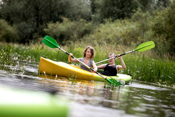 Two happy girls enjoying kayak on the river