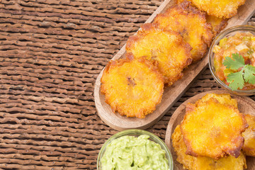 Poster - Patacon fried pieces of crushed green banana. Guacamole. On the wooden table (toston, tachino)