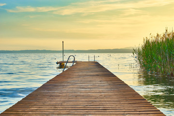 Wall Mural - Long wooden pier at Lake Garda in Italy at sunset / slightley blurred picture with nice bokeh