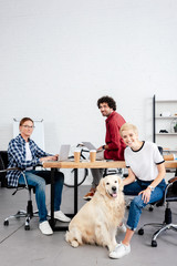 young start up team and dog looking at camera while working in office