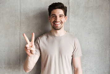 Cheerful young man showing peace gesture.