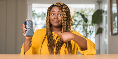 Wall Mural - African american woman showing broken smartphone very happy pointing with hand and finger