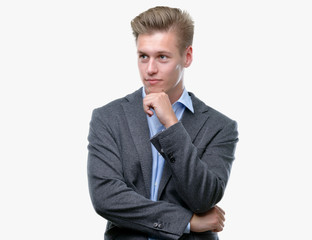 Sticker - Young handsome blond business man with hand on chin thinking about question, pensive expression. Smiling with thoughtful face. Doubt concept.