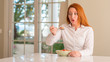 © Krakenimages.com - Redhead woman eating cereals with raspberries at home scared in shock with a surprise face, afraid and excited with fear expression