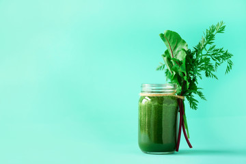 Wall Mural - Smoothie with beet greens and carrot tops on blue background, copy space. Summer vegan food concept. Healthy detox eating, alkaline diet. Fresh squeezed juice, drink from vegetables. Leafy greens.