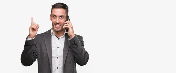 Poster - Handsome young man using smartphone surprised with an idea or question pointing finger with happy face, number one