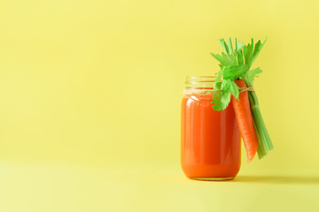 Wall Mural - Fresh carrot juice with carrots, celery on yellow background. Vegetable smothie in glass jar. Copy space. Summer food concept. Healthy detox eating, alkaline diet