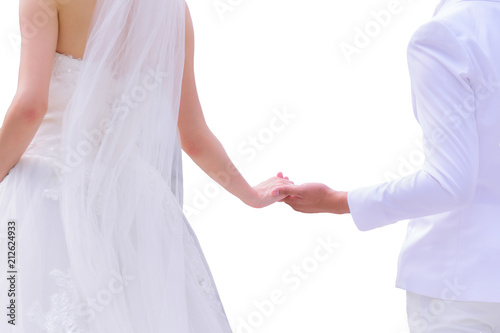 Fotografie, Obraz Asian bride in white wedding dress and groom in white suit holding hands isolate