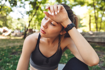 Wall Mural - Close up of a tired young fitness girl wiping her forehead