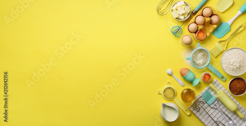 Fotografía Banner of baking ingredients - butter, sugar, flour, eggs, oil, spoon, rolling pin, brush, whisk, towel over yellow background