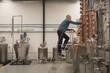 © Wavebreak Media - Side view of male worker checking distillery machine