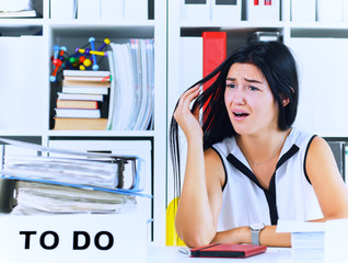 Young female office worker shocked by the huge amount of paper work. Deadline concepts.