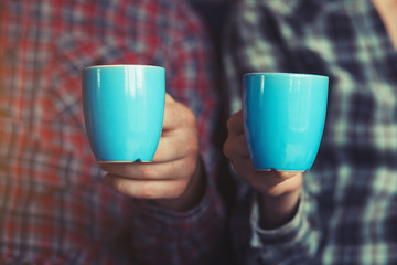 couple with two cups of morning coffee in plaid shirts