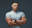 © Fxquadro - Portrait of a muscular handsome bodybuilder in sportswear, standing with crossed arms in a studio.