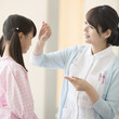 © amanaimages - 女の子の熱を測る看護師
