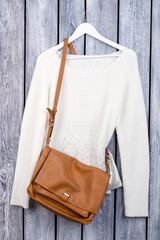 Wall Mural - Sweater and leather handbag. Top view women's pullover and brown purse.