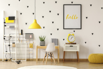 Wall Mural - Yellow clock on cabinet next to white chair and desk in kid's room interior with lamp. Real photo