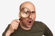 Shocked bald guy looking through magnifying glass