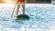 Detail of young man standing on paddleboard.