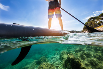 Young man on paddleboard, half under and half above water composition