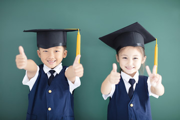 Wall Mural - Happy boy and girl in graduation cap showing thumbs up