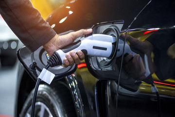 Hand holding charging electric car battery at station