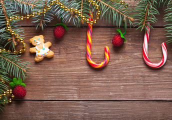 Wall Mural - Christmas tree branch, candy cane and decorative elements on a wooden table or board for background. New year theme. Space for text