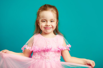 Wall Mural - Baby girl in beautiful pink dress on blue isolated