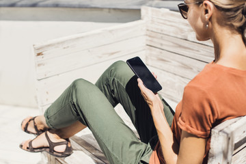 Close up of beautiful girl using mobile phone in a city. Young woman texting on smartphone outdoor