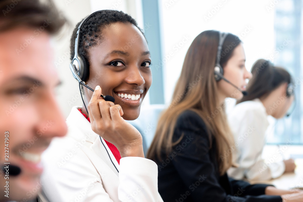 Smiling beautiful African American woman working in call center with diverse team - obrazy, fototapety, plakaty 